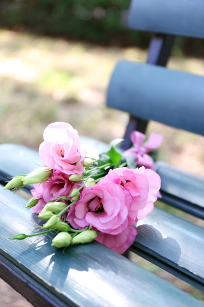 Beau bouquet de fleurs d'eustoma sur banc en bois dans le parc