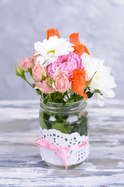 Beau bouquet de fleurs lumineuses en pot sur table sur fond gris