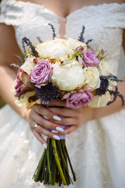 Beau bouquet de fleurs de mariage dans les mains des jeunes mariés