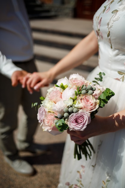 Beau bouquet de fleurs de mariage dans les mains des jeunes mariés