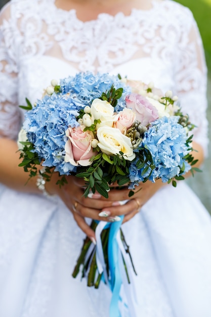 Photo beau bouquet de fleurs de mariage dans les mains des jeunes mariés