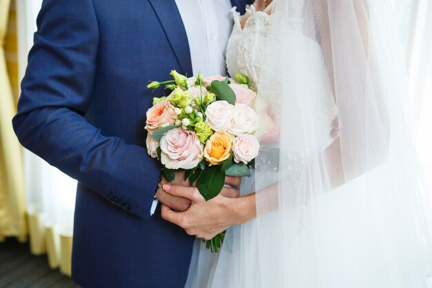 Beau bouquet de fleurs de mariage dans les mains des jeunes mariés