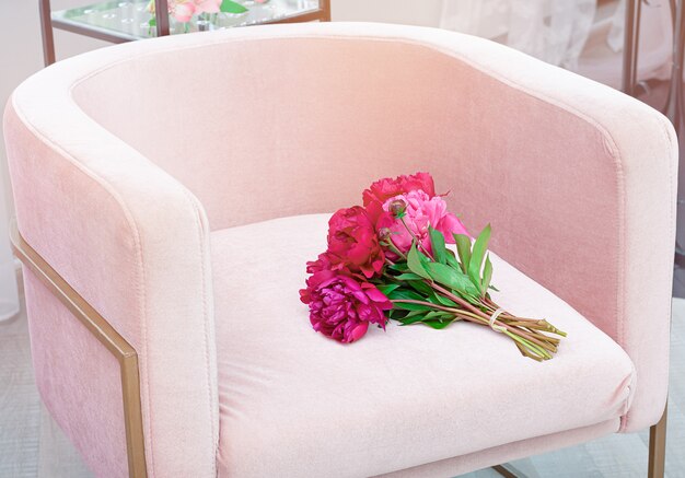 Beau bouquet de fleurs de pivoine fraîche sur une chaise rose pâle