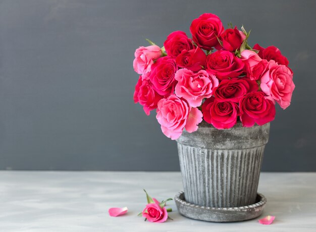 Beau bouquet de fleurs de rose rouge dans un vase sur gris