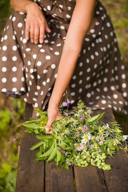 Beau bouquet de fleurs sauvages d'été dans les mains de la femme sur un fond en bois