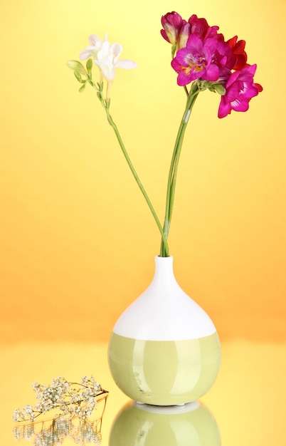 Beau bouquet de freesia dans un vase sur fond orange