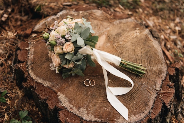 Beau bouquet de mariage avec des anneaux de mariage protea et roses sur fond de forêt