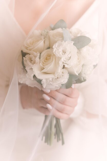 Beau bouquet de mariage blanc de roses entre les mains de la mariée