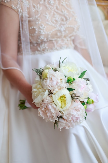 Beau bouquet de mariage dans la main de la mariée de pivoines blanches