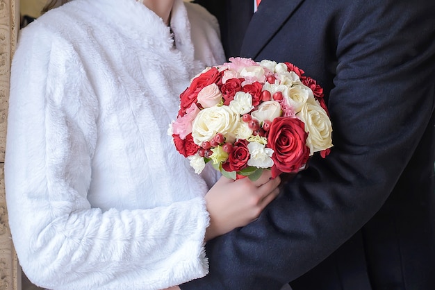 Beau bouquet de mariage entre les mains de la mariée et le marié gros plan