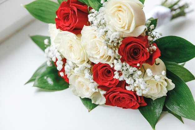 Beau bouquet de mariage de fleurs dans des couleurs rouges blanches se trouvant sur le fond blanc de surface. Déclaration d'amour, printemps. Carte de mariage, voeux de la Saint-Valentin. Détails du jour du mariage.