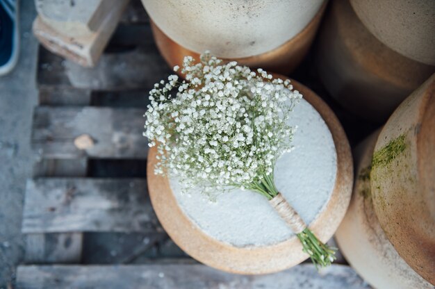 Un beau bouquet de mariage de gypsophile repose sur une cruche en argile.