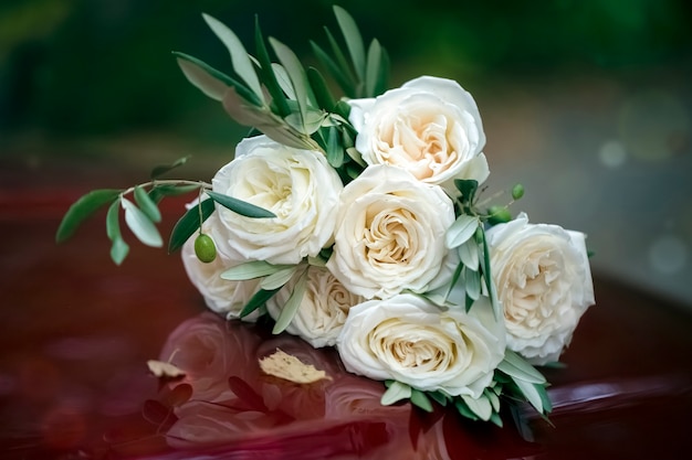 Beau bouquet de mariage de roses blanches sur un capot rouge d'une voiture. Fermer. Arrière-plan, texture. Teinture