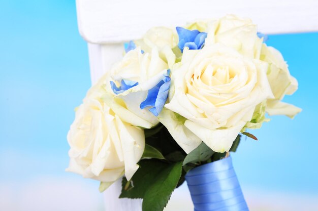 Beau bouquet de mariage avec des roses sur une chaise en bois, sur fond de nature