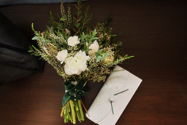 Beau bouquet de mariage se trouve sur un fond en bois, à une pochette blanche