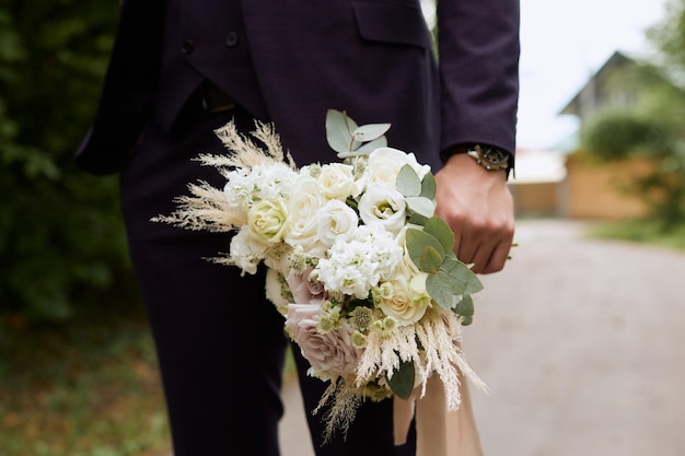 Un beau bouquet de mariée entre les mains du marié