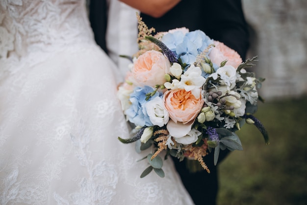 beau bouquet de mariée avec des fleurs rouges, roses et blanches, des roses et des eucalyptus, des pivoines, des lis calla