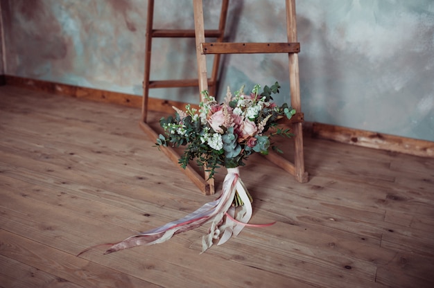 Beau bouquet de mariée sur un fond en bois avec des rubans blancs et roses