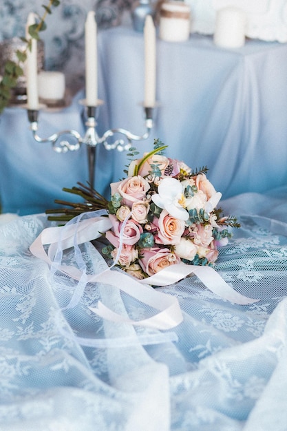 Beau bouquet de mariée lumineux avec roses et ruban dans des bougies chandeliers intérieurs