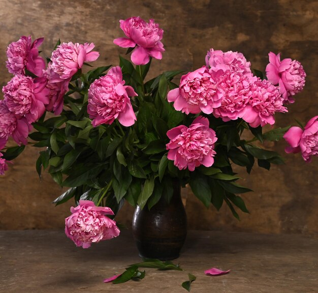 Photo beau bouquet de péonies roses dans un vase sur un fond en bois