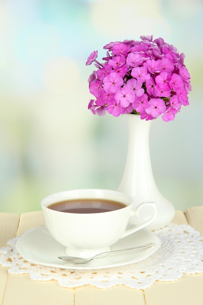 Beau bouquet de phlox avec tasse de thé sur table sur fond clair