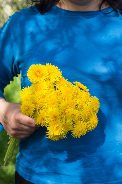 Photo beau bouquet de pissenlits jaunes en forme de boule dans la main de la jeune fille