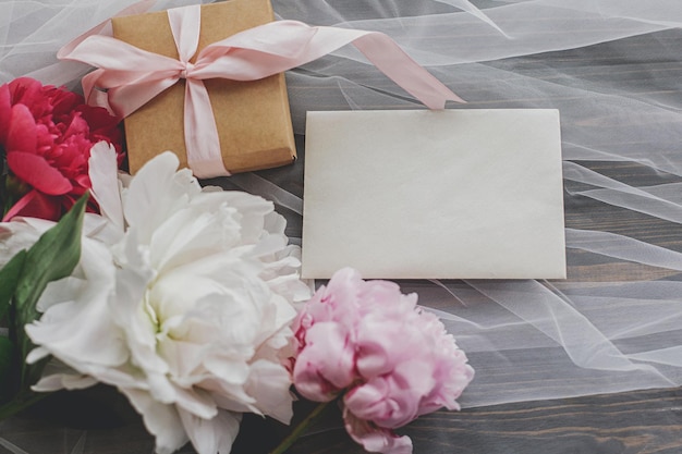 Beau bouquet de pivoines cadeau et carte sur tulle doux sur la vue de dessus en bois foncé Bonne fête des mères