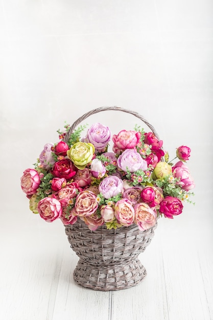 Beau bouquet de pivoines dans un panier ancien sur un plancher en bois.