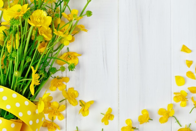 Beau bouquet de renoncule jaune couché sur des planches en bois blanc