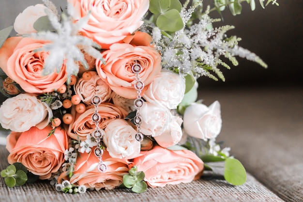 Photo beau bouquet de roses blanches et rouges et boucles d'oreilles dessus comme accessoires de la mariée. photo horizontale