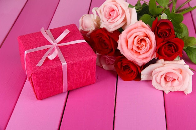 Beau bouquet de roses avec cadeau sur table close-up