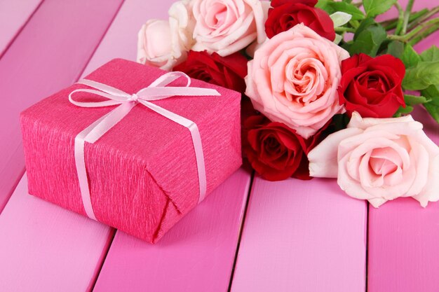 Beau bouquet de roses avec cadeau sur table close-up