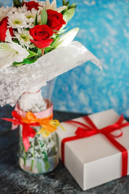 Beau bouquet de roses avec des chrysanthèmes et une boîte avec un cadeau