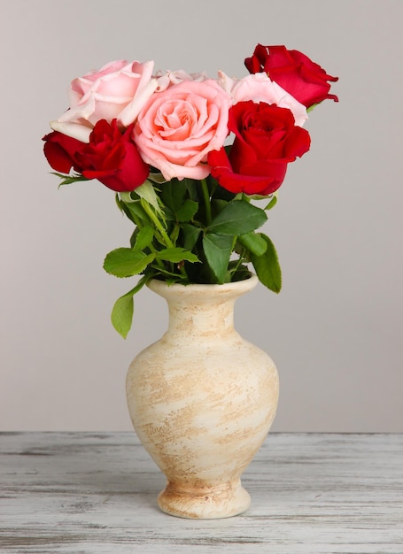 Beau bouquet de roses dans un vase sur table sur fond gris