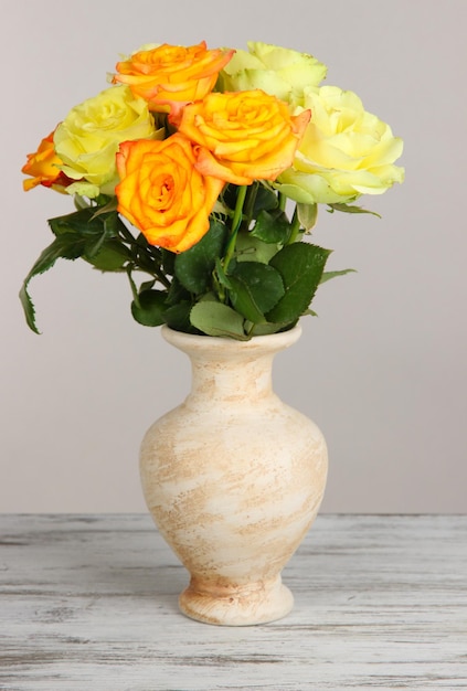 Beau bouquet de roses dans un vase sur table sur fond gris