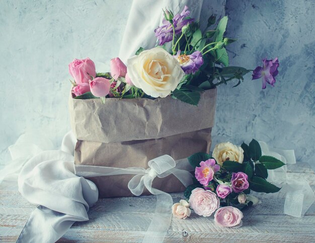 Photo un beau bouquet de roses roses dans un sac en papier artisanal est une nature morte