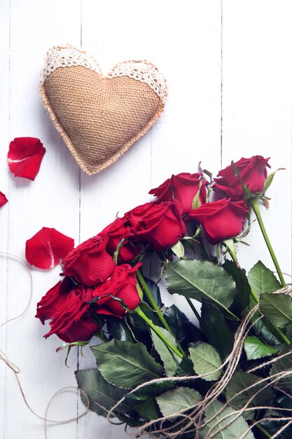 Beau bouquet de roses rouges et coeur d'un sac sur fond de bois