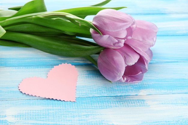 Beau bouquet de tulipes violettes et carte vierge sur fond de bois bleu