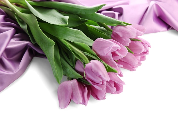 Beau bouquet de tulipes violettes sur tissu satiné, isolé sur blanc
