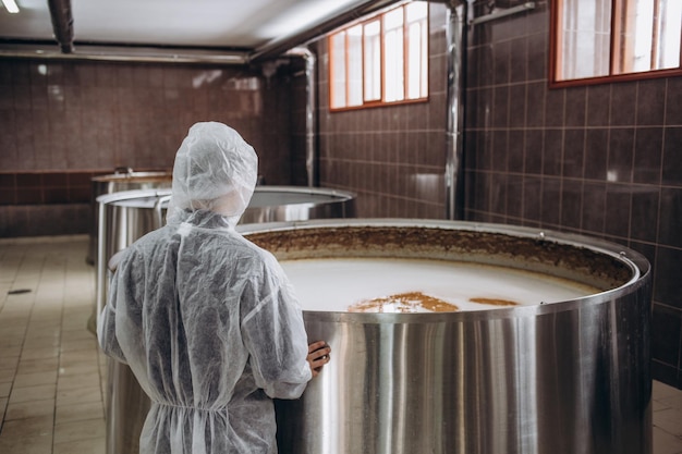 Beau brasseur barbu contrôlant le processus de fermentation de la bière dans son usine de bière artisanale