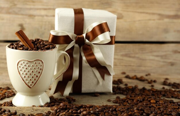 Beau cadeau avec des grains de café et d'arc dans la tasse, sur le fond en bois