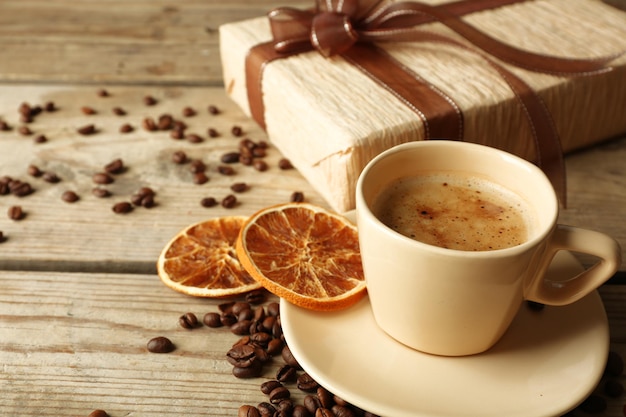 Beau cadeau, tasse de café et grains de café sur fond de bois