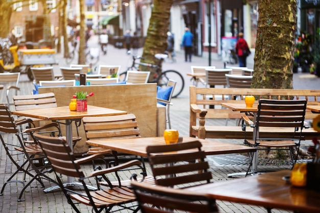 Photo beau café dans la rue de la ville de delft aux pays-bas. tables et chaises dans la rue