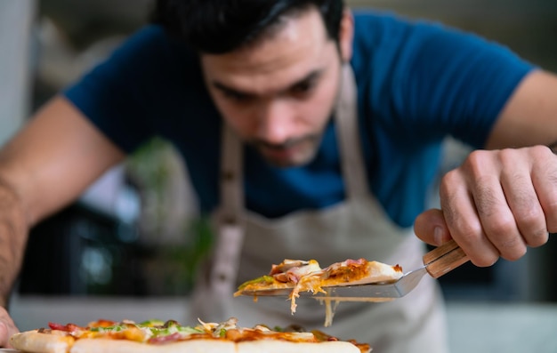 Photo beau chef coupe la pizza à la mozzarella de la cuisinière ou du four pour le déjeuner, le dîner, le restaurant