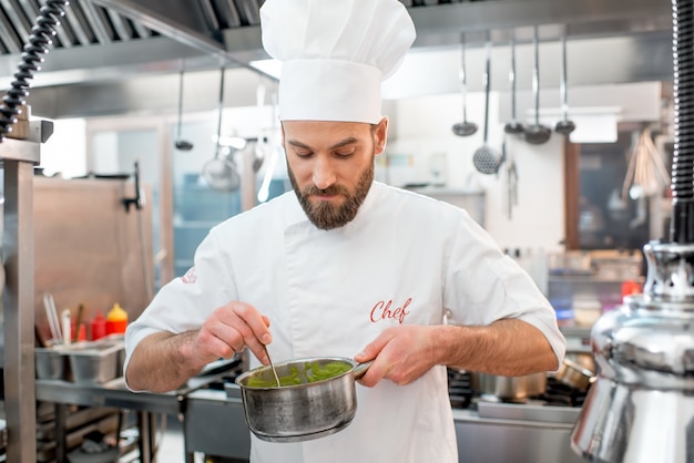 Beau chef cuisinier faisant des saucisses dans la cuisine du restaurant