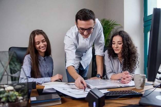 Beau chef d'entreprise dans des verres explique les tâches de travail de ses employés. Gens créatifs ou concept d'entreprise publicitaire. Travail en équipe. Jeunes belles personnes travaillant ensemble au bureau.