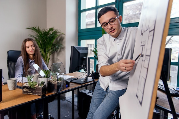 Beau chef d'entreprise dans des verres explique les tâches de travail de ses employés. Gens créatifs ou concept d'entreprise publicitaire. Travail en équipe. Jeunes belles personnes travaillant ensemble au bureau.