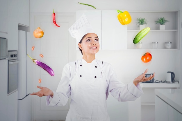 Beau chef jonglant avec des ingrédients alimentaires dans la cuisine