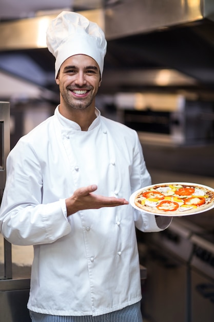 Beau chef présentant une pizza