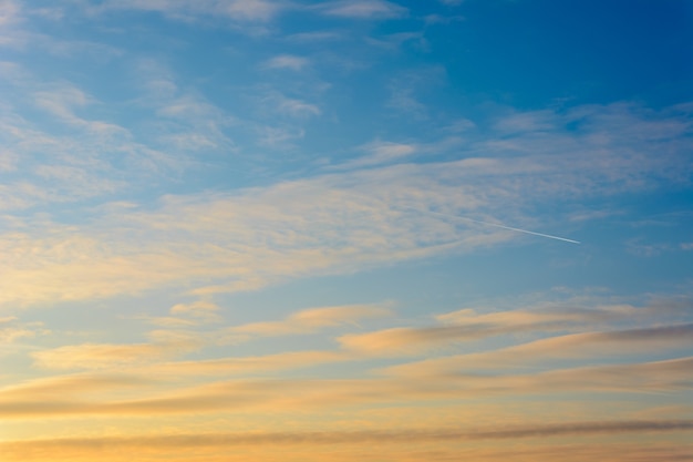 Beau ciel avec un avion qui passe. Le ciel au coucher du soleil. Nuages lumineux.